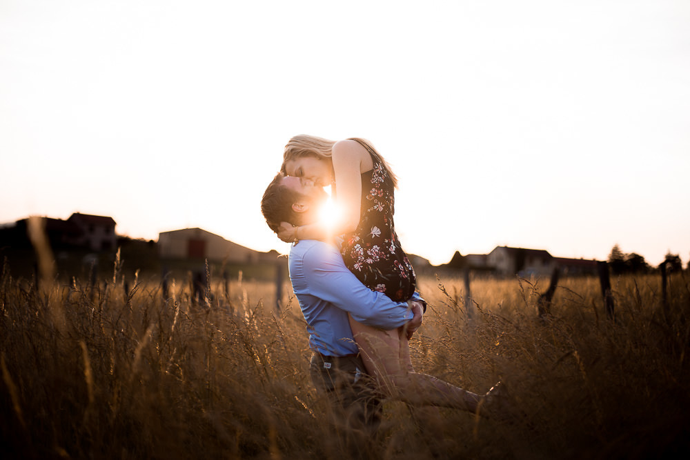 Photo de couple dans un champ du beaujolais au coucher de soleil